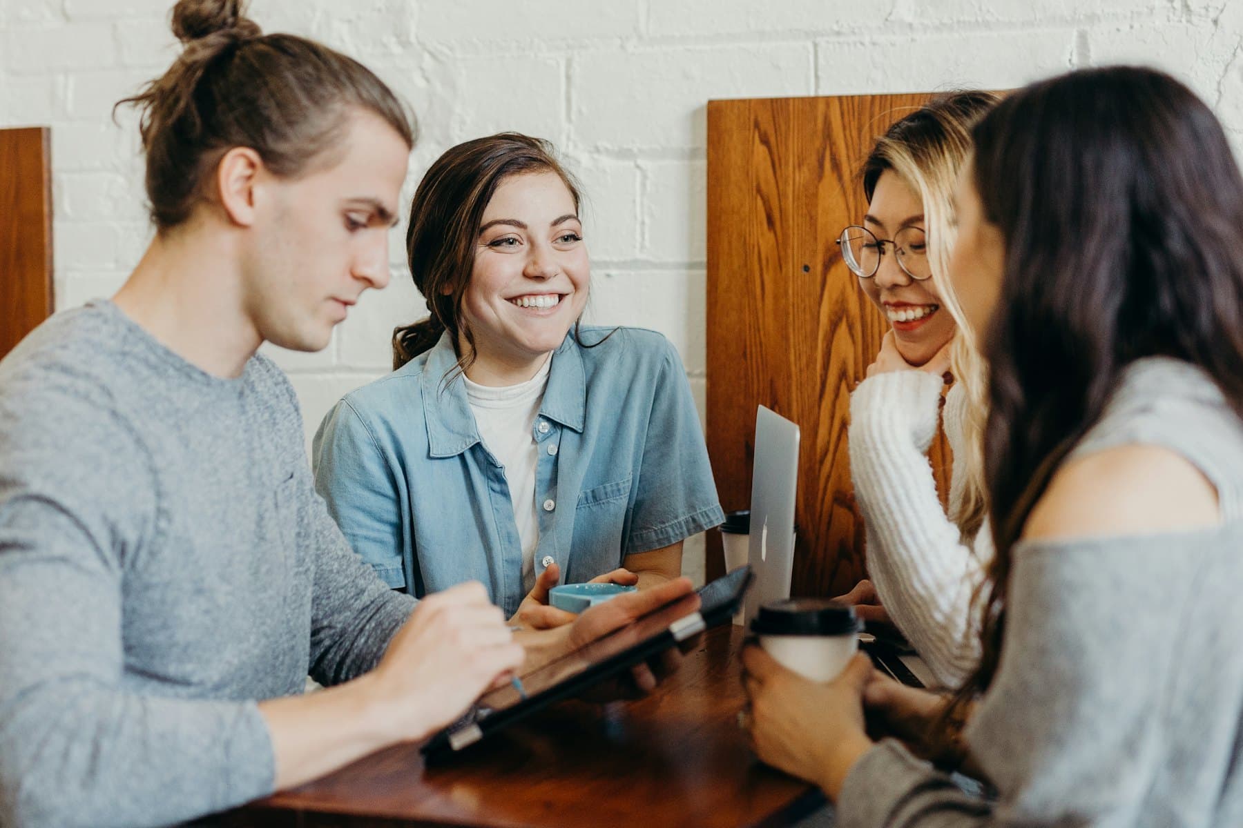 Four friends laughing together around a table